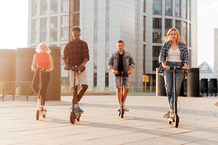 eine Gruppe von 4 Menschen fährt gemeinsam auf E-Scootern