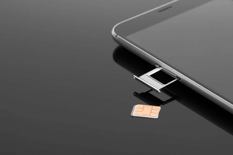 iPhone mit offenem SIM-Karten-Slot und einer SIM-Karte daneben