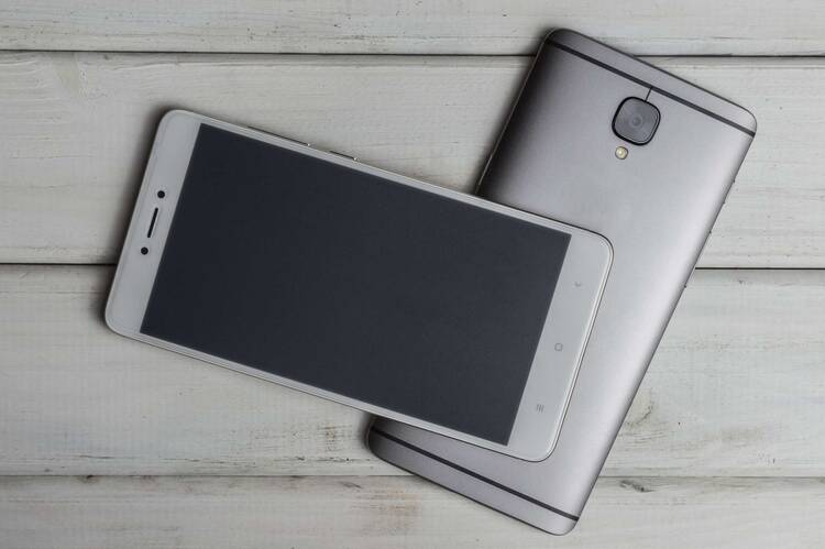 zwei Smartphones liegen aufeinander auf grauem Untergrund