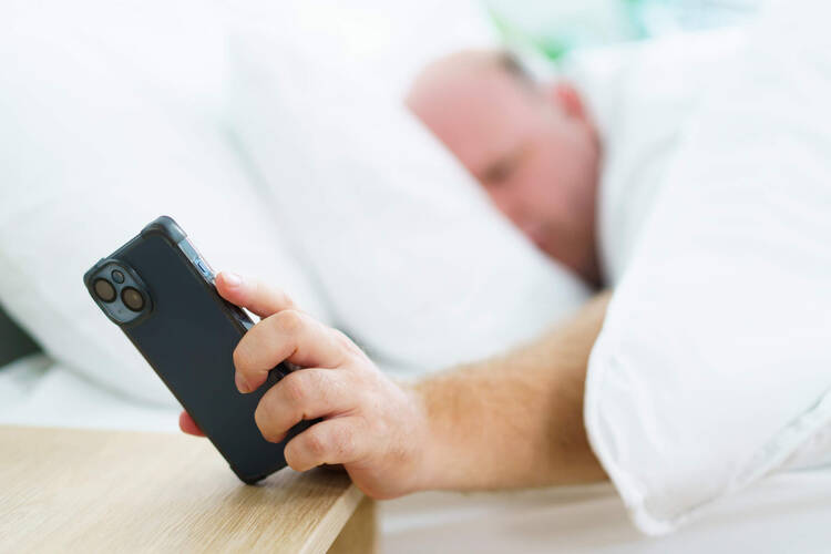 Mann schaut auf sein Smartphone im Bett