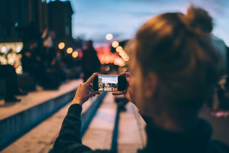 eine Frau fotografiert draußen etwas mit dem Smartphone