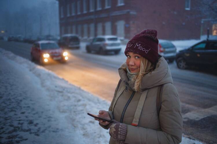 Frau in Winterklamotten auf der Straße mit Smartphone in der Hand