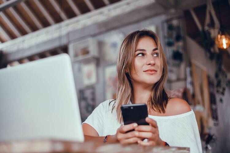 Frau mit Handy in der Hand schaut zur Seite