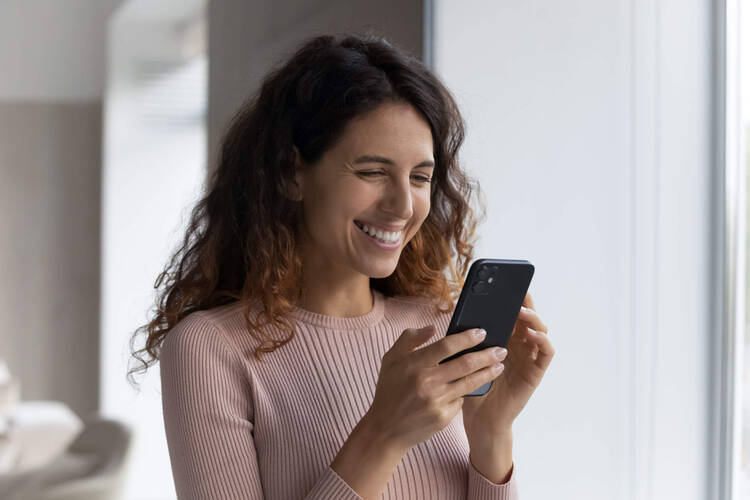 Frau lächelt und benutzt ein Smartphone