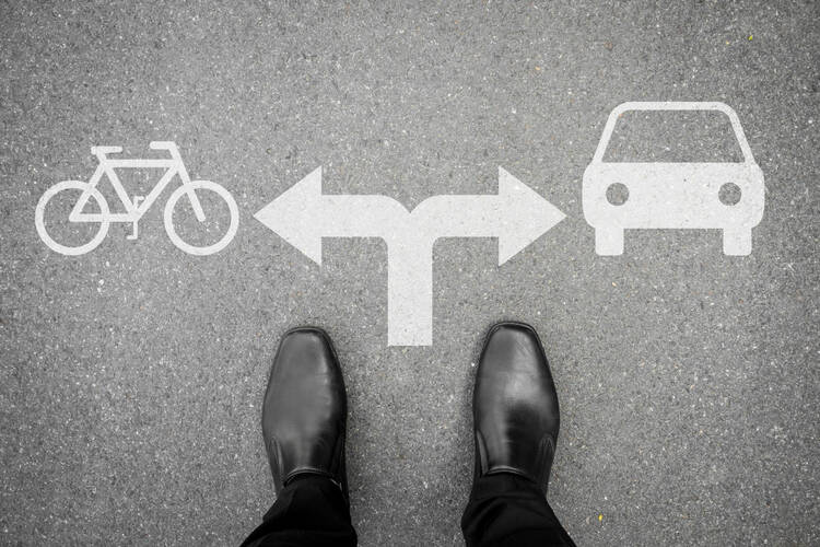 Person steht vor der Wahl: Auto oder Fahrrad