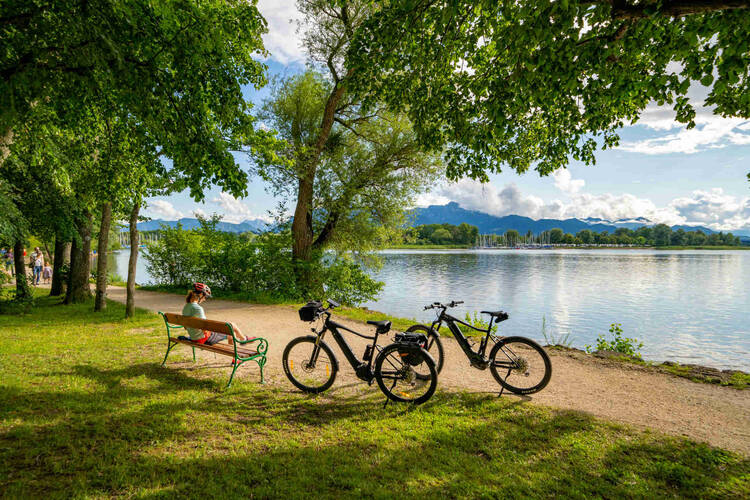 Pause von zwei Fahrradfahrern neben einer Bank am Tegernsee