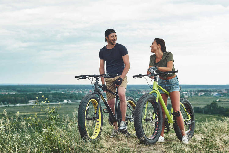 Mann und Frau auf Fatbike auf Wiese.