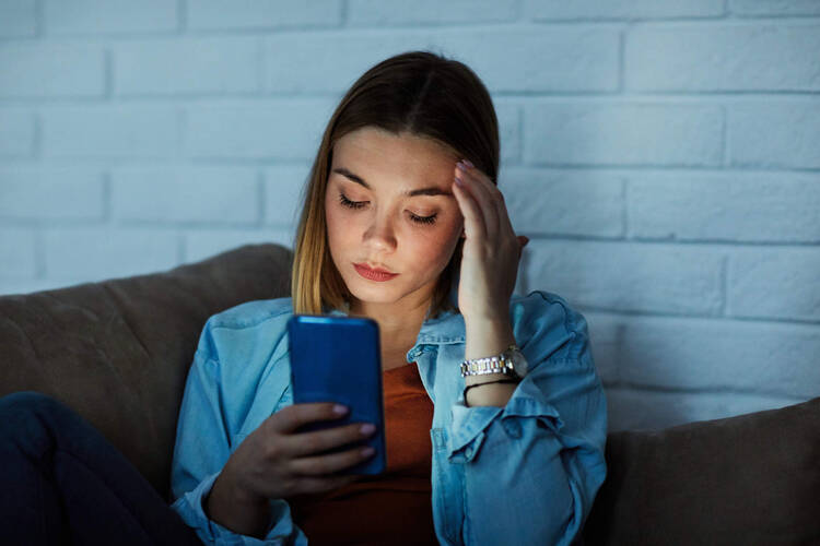 Frau guckt traurig aufs Handy