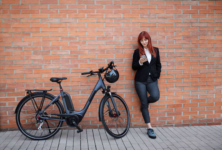 Frau steht neben Fahrrad an Wand