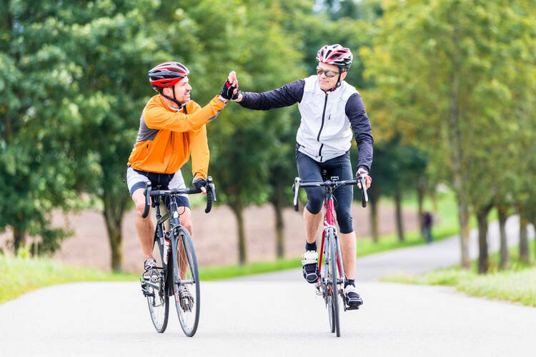 Zwei Rennradfahrer klatschen sich am Ziel ab.