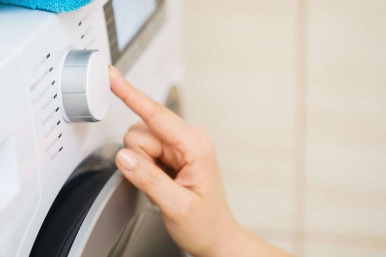 Hand dreht an Knopf einer Waschmaschine