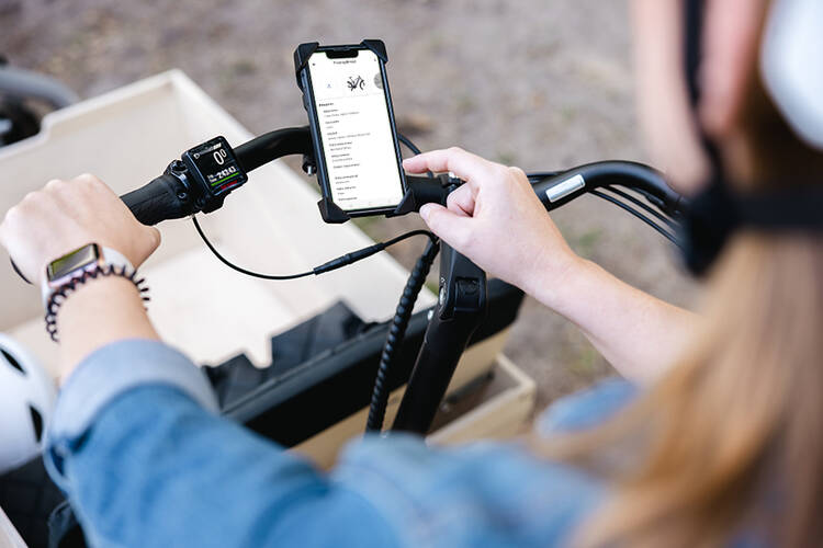 Fahrradfahrerin schaut auf Smartphone mit Bikemanager App