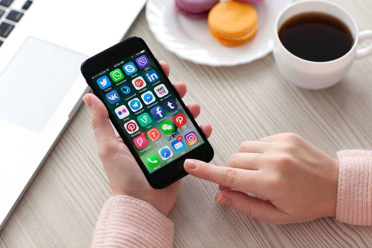 iPhone mit Apps im Hintergrund wird von zwei Händen bedient