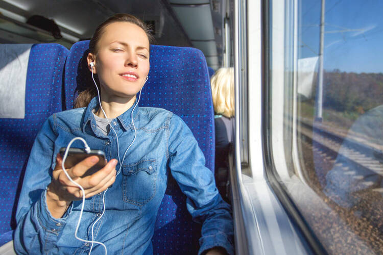 Frau sitzt im Zug und hört Musik