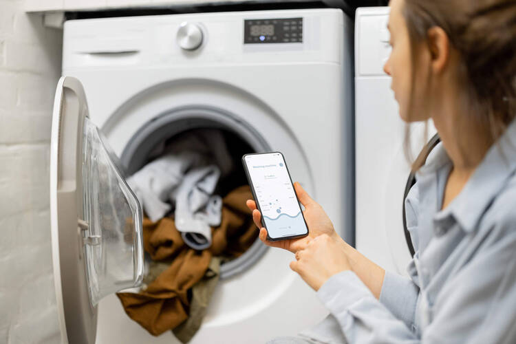 Frau steuert Waschmaschine mit App