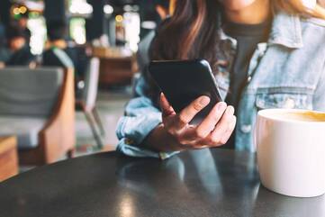 Fraut hält Smartphone im Cafe
