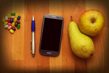 Schwarzes Smartphone mit Kugelschreiber und Snacks