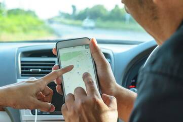 Eine Person zeigt auf die Navigations App auf einem Smartphone