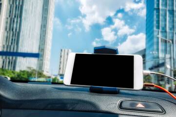 Smartphone in einer Halterung auf dem Amaturenbrett eines Autos