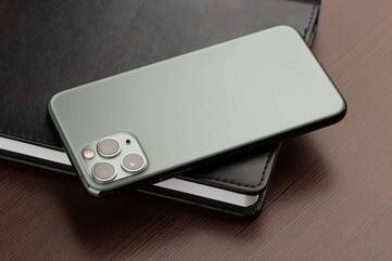 Schwarzes Apple iPhone 11 Pro Max liegt auf schwarzem Notizbuch