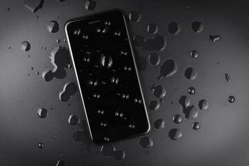 Dunkles Smartphone mit Wassertropfen bedeckt