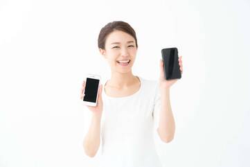 Frau hält lächelnd zwei verschiedene Smartphones hoch