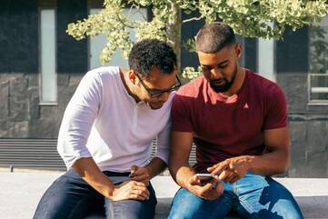 Zwei Männer gucken zusammen auf ein Smartphone