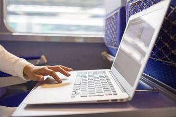 Person arbeitet, im Zug, an einem Notebook der Asus VivoBook Serie.