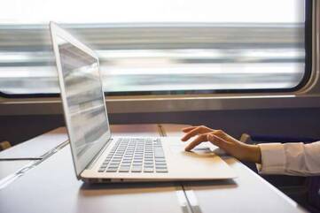 Person arbeitet, im Zug, an einem Notebook der Asus ZenBook Pro Serie.