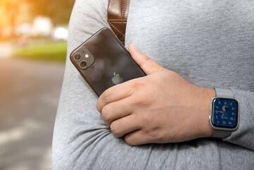 Person hält Smartphone in der Hand und trägt eine Apple Watch