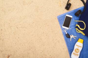 iPhone liegt neben einem Schlüsselbund auf einem Handtuch am Strand