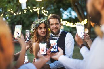 ein Hochzeitspaar wird von mehrern Personen mit ihren Smartphones fotografiert