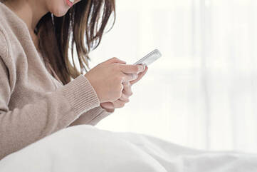 Frau mit Smartphone im Bett