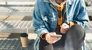 Person mit Smartphone in der Hand sitzend