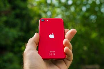 Hand hält rotes iPhone SE 2020 mit Rückseitenansicht