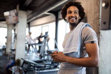 Mann mit Smartphone in der Hand im Fitnessstudio