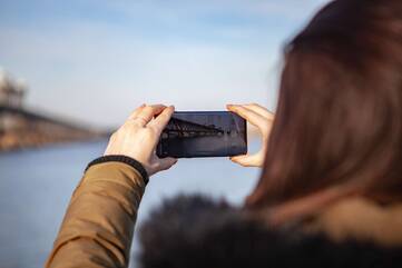 Frau nimmt mit Handy Bild vom See auf