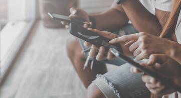 Drei sitzende junge Leute an Smartphones