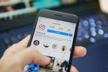 Instagram wird auf einem Smartphone vor einem Laptop genutzt