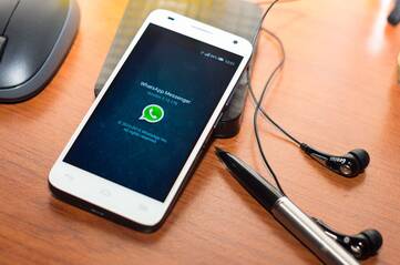Smartphone mit WhatsApp Splashscreen liegt auf einem Tisch