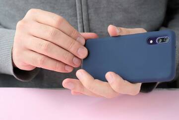 Person entfernt ein blaues Softcase von ihrem Smartphone