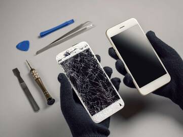 Ein kaputtes und ein heiles Smartphone Display werden nebeneinander gehalten