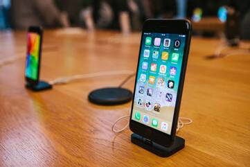 Zwei iPhones stehen aufrecht auf einem Holztisch