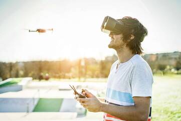 Person mit Virtual Reality Brille steuert eine Drohne