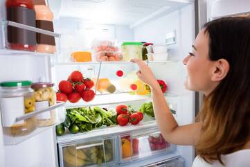 Frau verräumt Lebensmittel in einen Kühlschrank