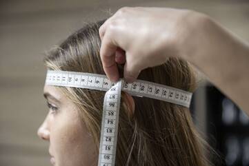 Der Kopfumfang wird bei einem jungen Mädchen mittels Maßband gemessen.