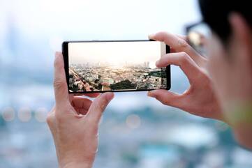 Mensch mit Smartphone macht ein Bild von einer Stadt.