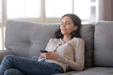 Frau entspannt auf Sofa mit Handy in den Händen