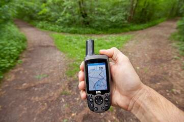 Person steht mit einem GPS-Gerät vor einem Scheideweg