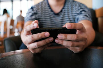 Mann hält Smartphone im Querformat mit beiden Händen